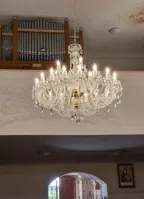 Großer Kristallleuchter in Goldausführung in einer Kirche mit Orgel und Stuckdekoration