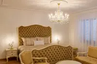 Marie-Theresien-Kristallleuchter in Goldausführung über einem Bett mit gepolstertem Kopfteil in einem klassischen Interieur